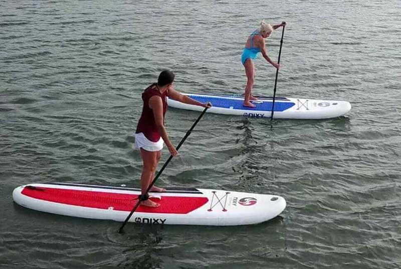 Older woman paddling on inflatable paddleboards 