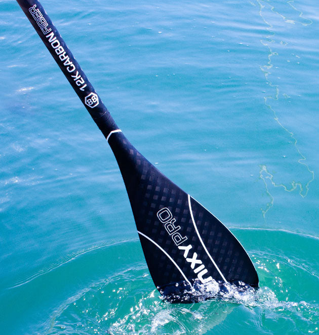 NIXY 12k Full Carbon Fiber Paddle for stand up paddle boarding splashing the surface of the water.