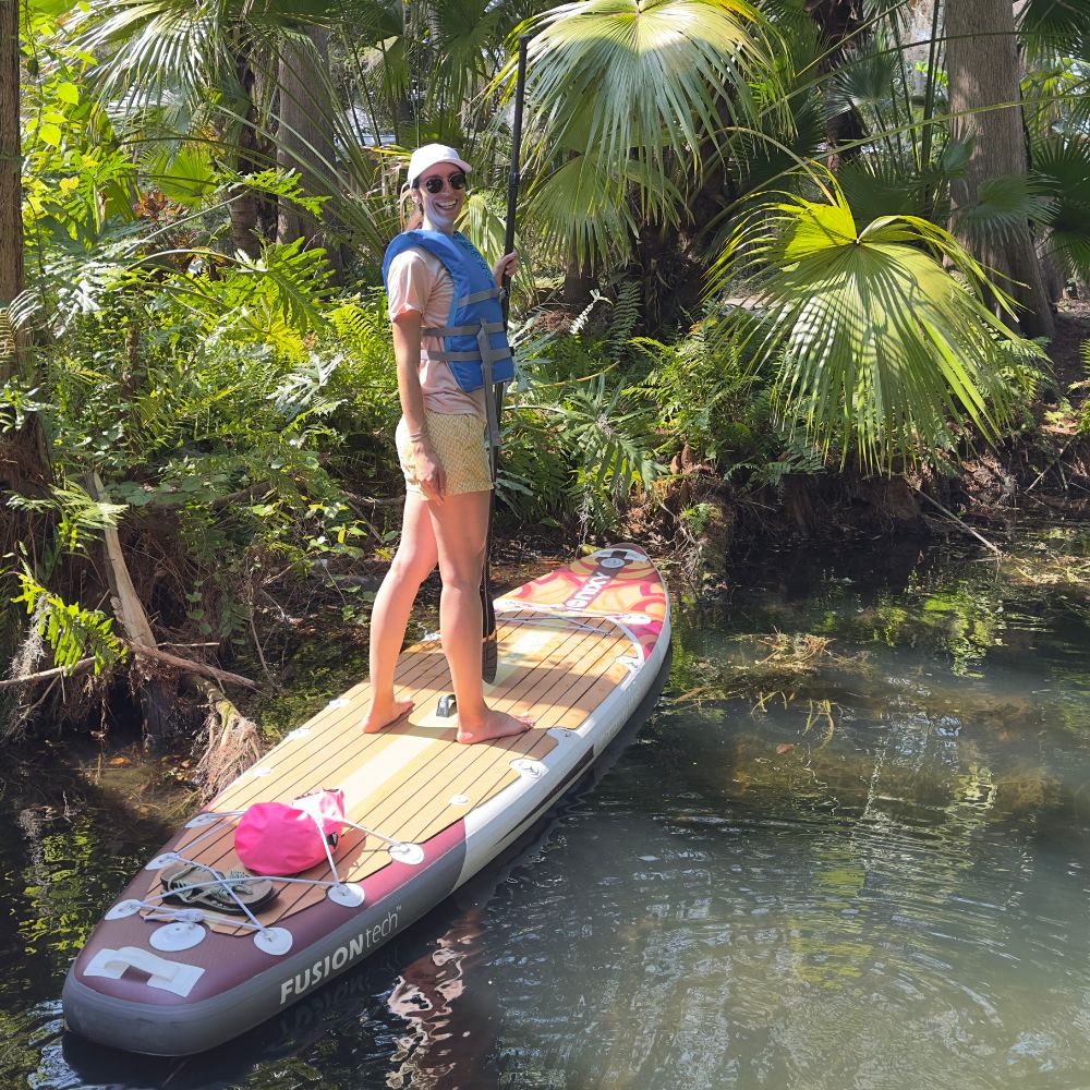 Beginner paddleboarder wearing a blue life jacket while smiling for the camera
