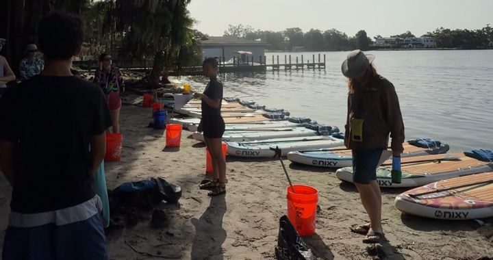 Volunteers using NIXY inflatable paddleboards to cleanup trash that is in the water practicing sustainable paddleboarding