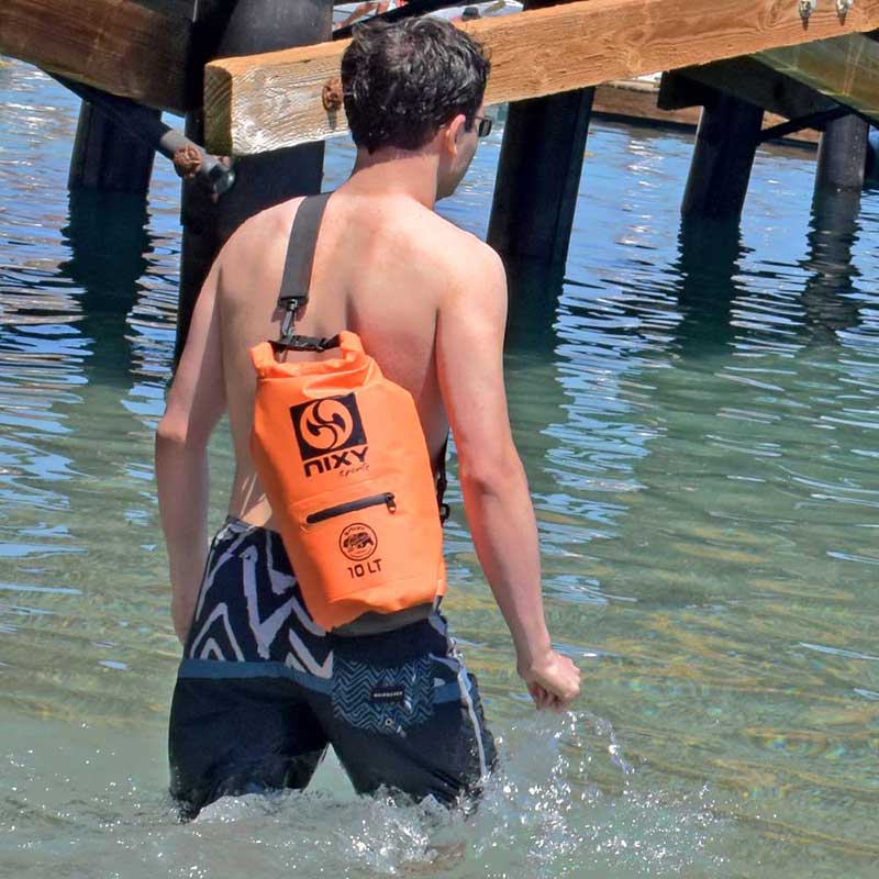 Man wading into the water with a NIXY waterproof dry bag across his back