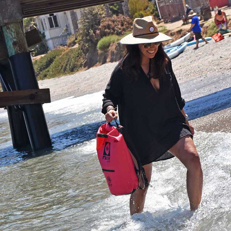 NIXY 10L Waterproof Dry Bag, a paddler wading along the shoreline carrying the roll-top bag