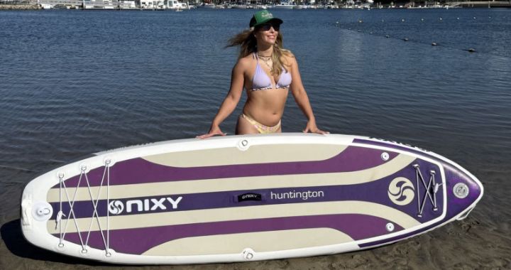 NIXY Huntington G5 compact inflatable paddle board on calm lake with rider standing