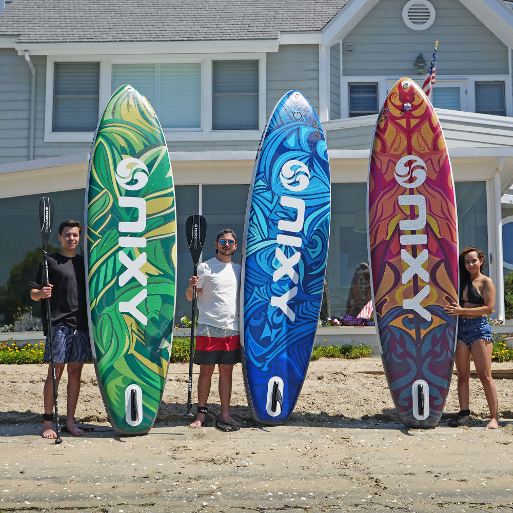 NIXY Inflatable stand-up paddleboards being held up at the beach