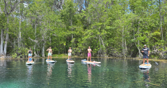 Landscape photo of a family standing on inflatable paddleboards