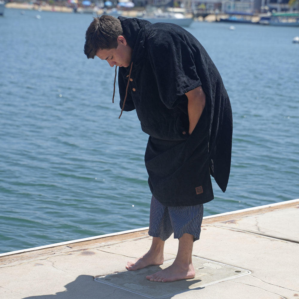 Man changing into swim shorts while wearing a NIXY adult towel changing poncho