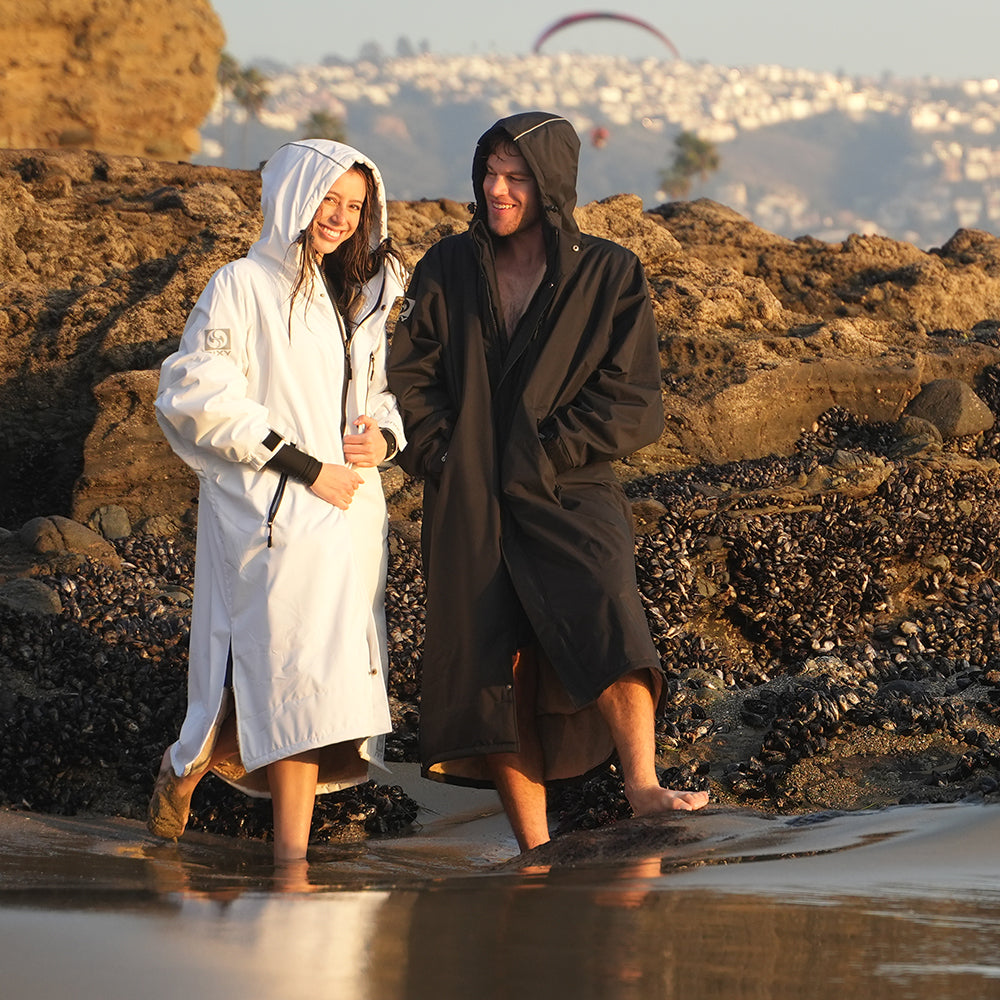 NIXY Adventure Changing Parka worn on a beach, a waterproof hooded changing robe for cold-water sports