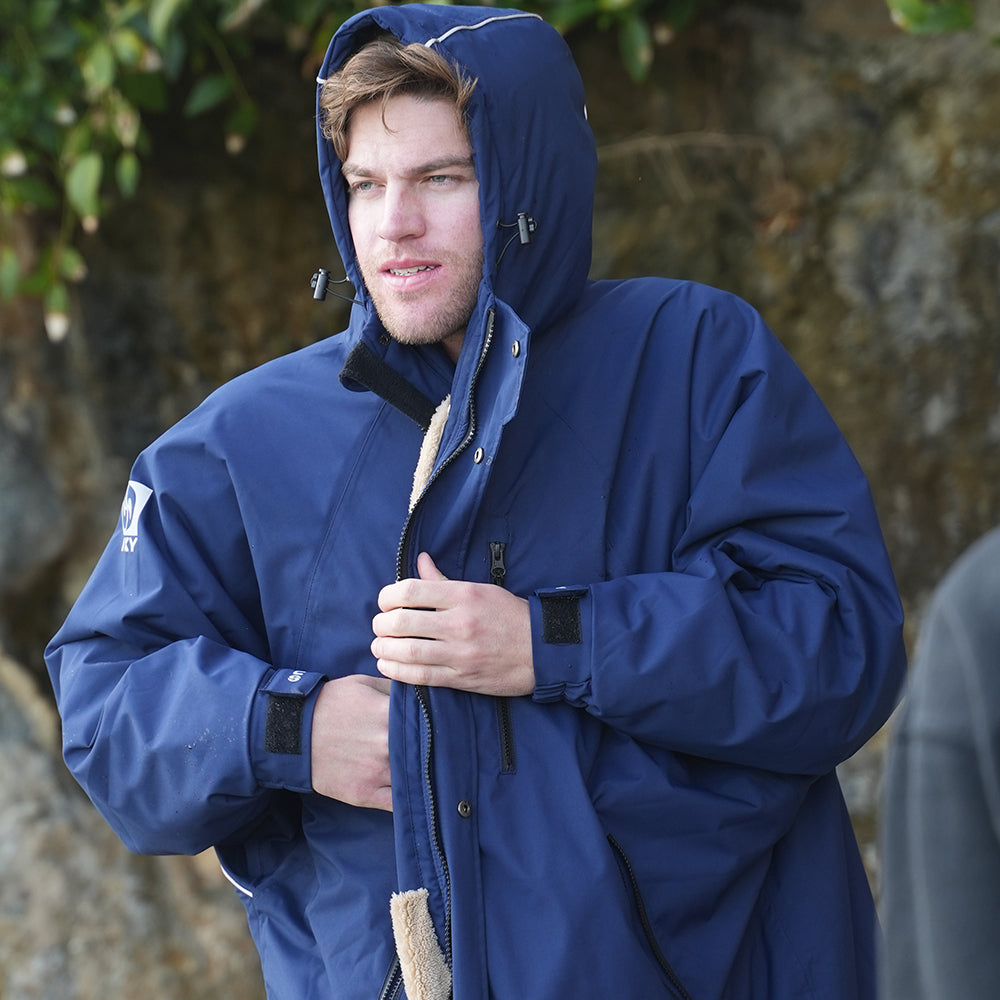 Man wearing a NIXY Adventure Changing Parka with the hood up to warm up after a cold-water session