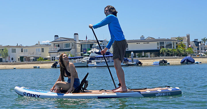 A man and a women riding on a NIXY inflatable paddleboard on the water 