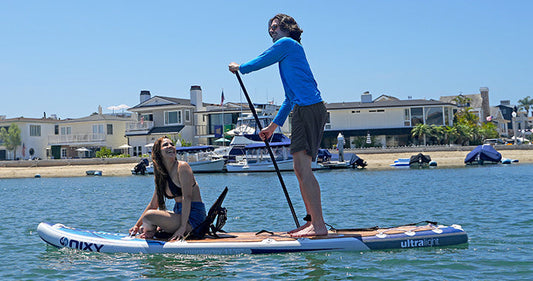 A man and a women riding on a NIXY inflatable paddleboard on the water 