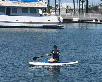 Paddleboarder gliding on the water's surface in front of a boat