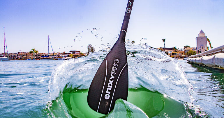 NIXY carbon fiber adjustable paddle splashing the water in a lifestyle photo.