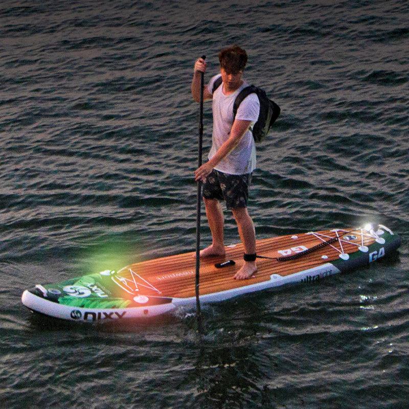 NIXY Navigation Lights showing white, red, and green LEDs mounted on a paddle board in low light
