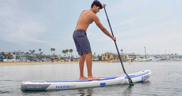 Man paddling on top of a NIXY inflatable stand up paddleboard