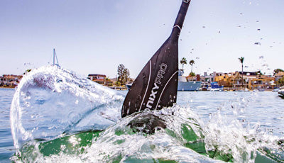 Carbon fiber SUP paddle splashing the water.