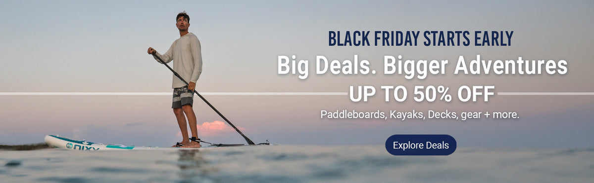 Promotional banner for a black Friday sale showing a man stand-up paddleboarding on calm water at sunset, with text reading 'BLACK FRIDAY STARTS EARLY', 'Big Deals. Bigger Adventures UP TO 50% OFF', and an 'Explore Deals' button.