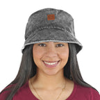 Smiling woman with long dark hair wearing NIXY Vibe Bucket Hat in Black front view, 100% cotton unisex trendy acid washed bucket hat with leather NIXY logo patch and wide brim for sun protection, stylish hat for beach, paddleboarding and SUP