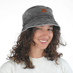 Woman with curly hair wearing NIXY Vibe Bucket Hat in Black smiling portrait, 100% cotton unisex trendy acid washed black bucket hat with wide brim and leather NIXY logo patch, stylish sun hat for beach, paddleboarding and SUP adventures