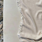 Textured fabric with frayed edge against a neutral background