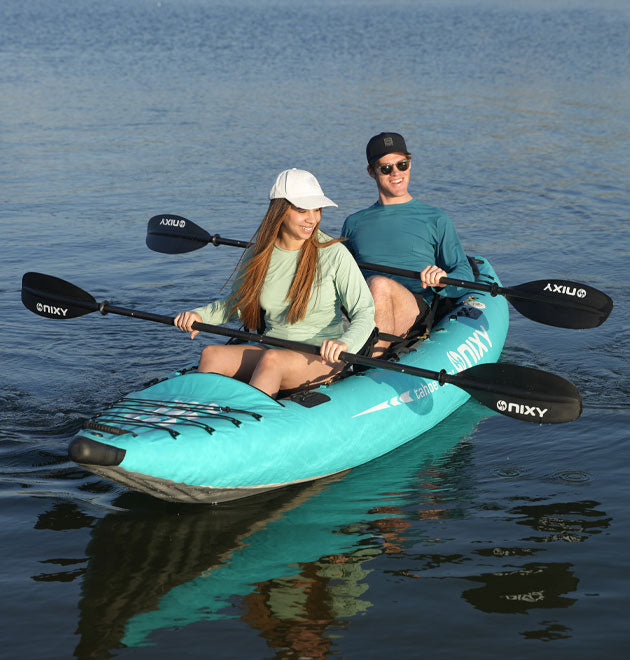 Man and women holding carbon fiber kayak paddles while sitting in a kayak