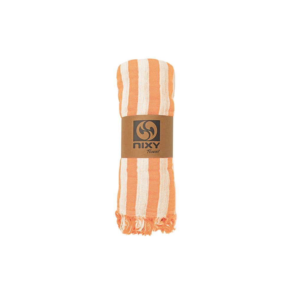 NIXY Melody recycled Turkish cotton orange and cream striped beach towel, rolled up with a brown paper band featuring the 'nixy towel' logo, set against a plain white background.