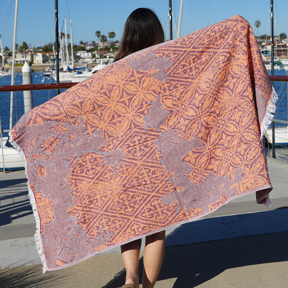 Person holding a patterned Turkish Cotton beach towel by a marina