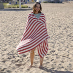 Woman wrapped in a red and white striped Turkish cotton beach towel on a sandy beach