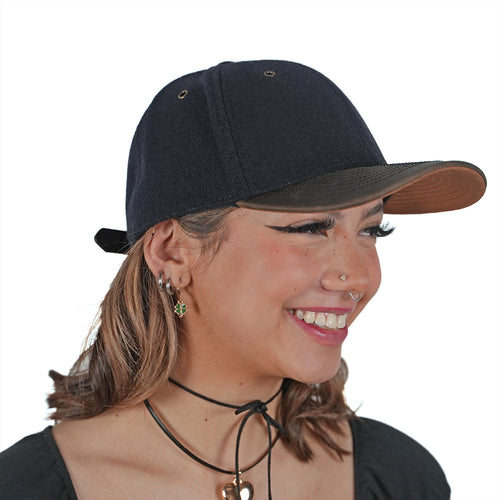 Woman smiling wearing NIXY Chill Wool and Leather Performance Cap in Midnight Navy with brown leather brim, stylish premium wool strapback hat with moisture-absorbent sweatband for everyday wear