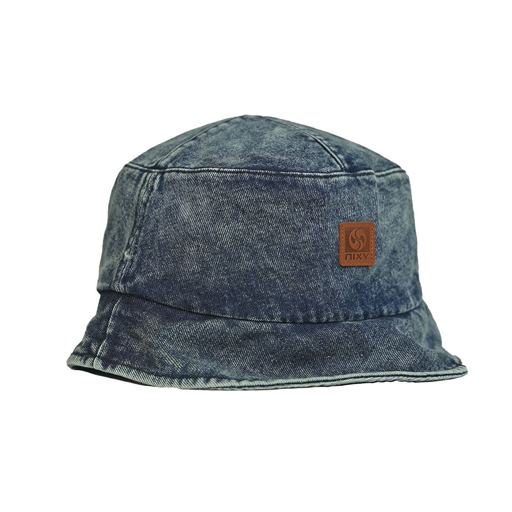 NIXY Vibe Bucket Hat in Denim blue angled front product view with leather NIXY logo patch and acid washed denim finish, 100% high grade cotton unisex trendy bucket hat with wide downward sloping brim, stylish sun hat for men and women