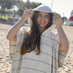 Person wearing NIXY Everest Adult Changing Poncho made with Turkish cotton on a beach with trees in the background