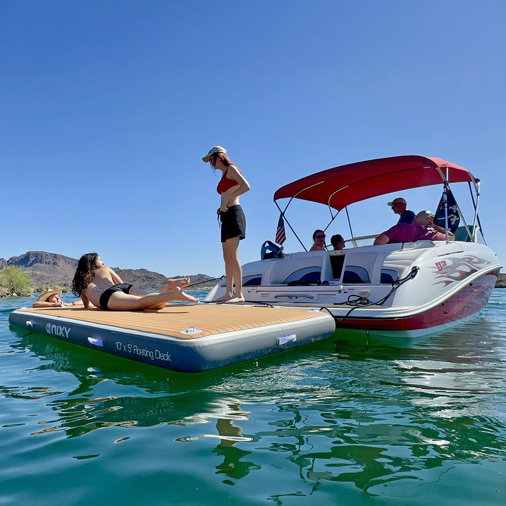People on a boat with a red canopy and an inflatable platform in the water.