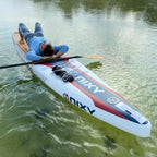 Person lying on a NIXY Malibu 14' Performance inflatable paddleboard on a lake