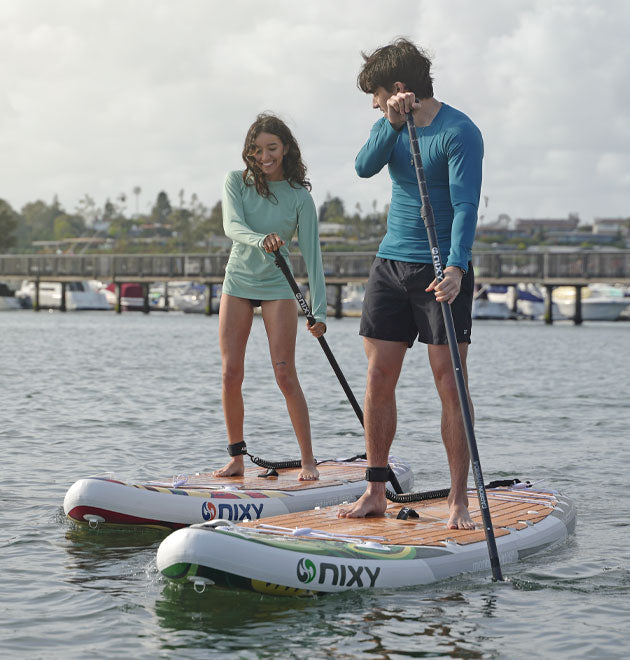 Man and women paddling on calm water on top of NIXY G5 isup
