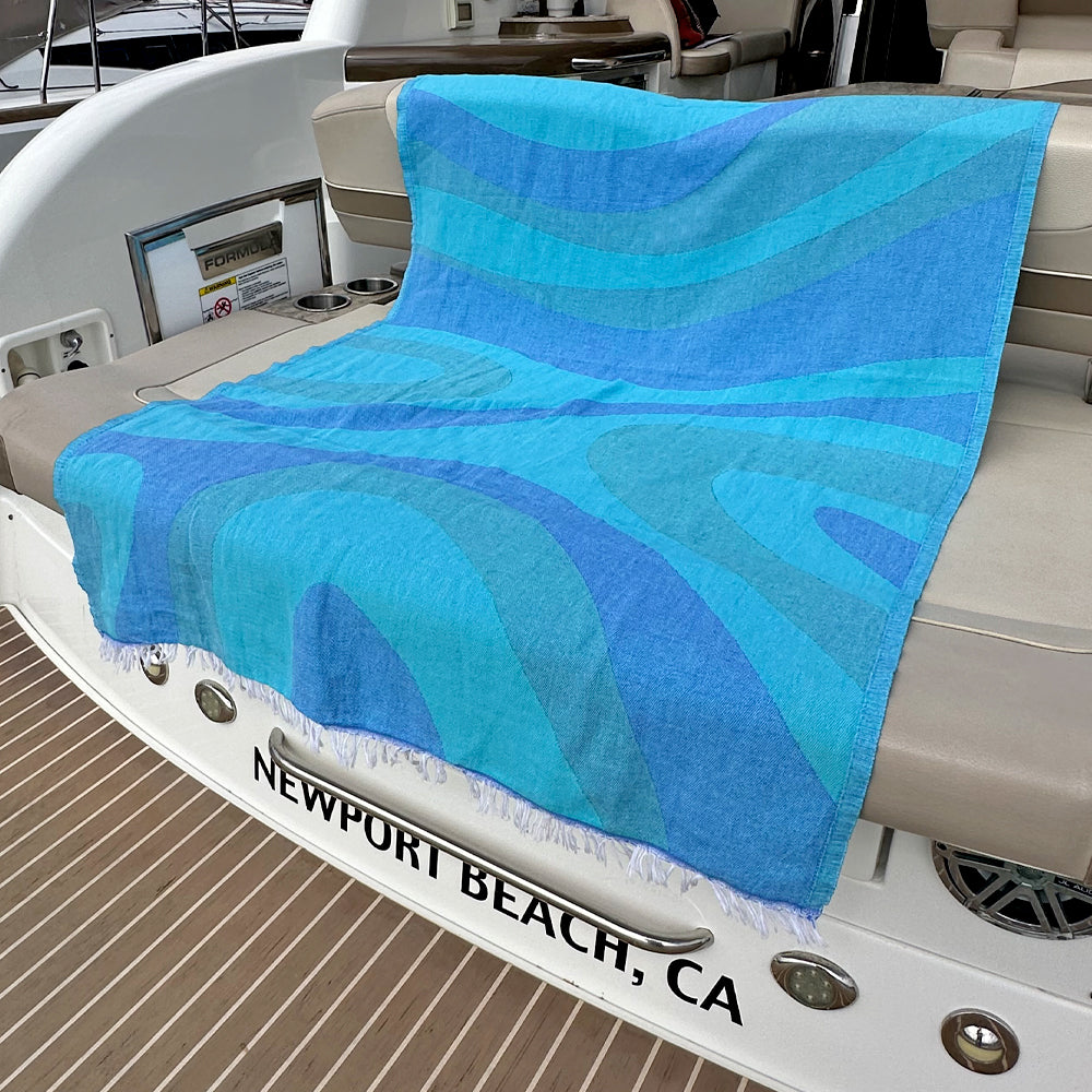 Blue patterned towel on a boat with 'Newport Beach, CA' on the floor.
