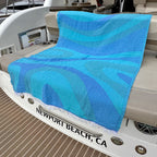 Blue patterned towel on a boat with 'Newport Beach, CA' on the floor.