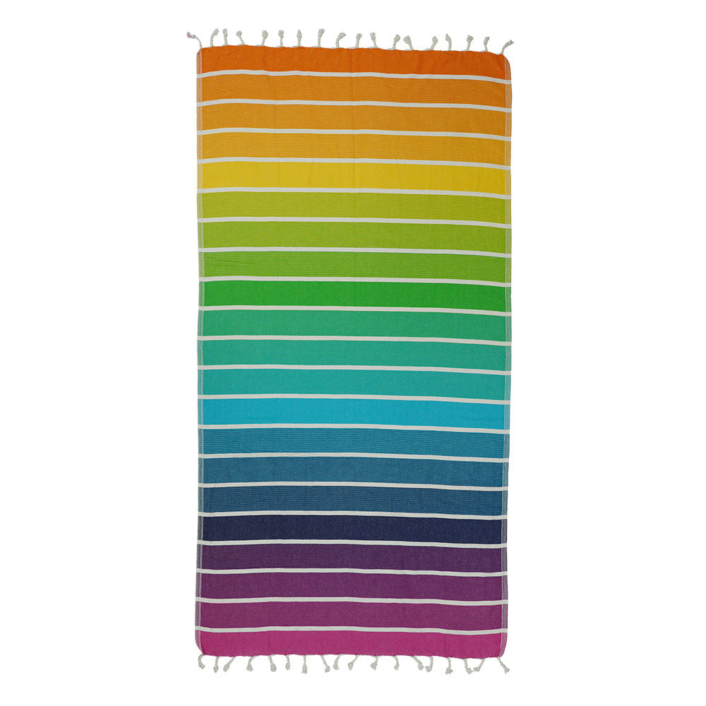NIXY Rainbow Turkish Beach Towel laid flat, layered rainbow stripe pattern in vivid colors on a white background