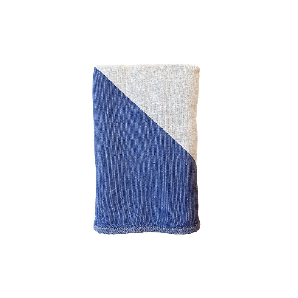 NIXY Parallax Recycled Turkish Cotton Beach Towel (Blue). A folded beach towel with bold diagonal stripes in blue and white, shown flat against a white background.
