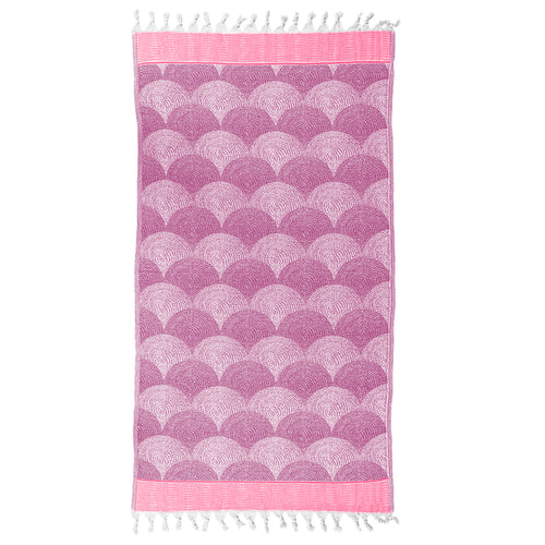 Pink and purple shell patterned Turkish towel with white tassels on a white background