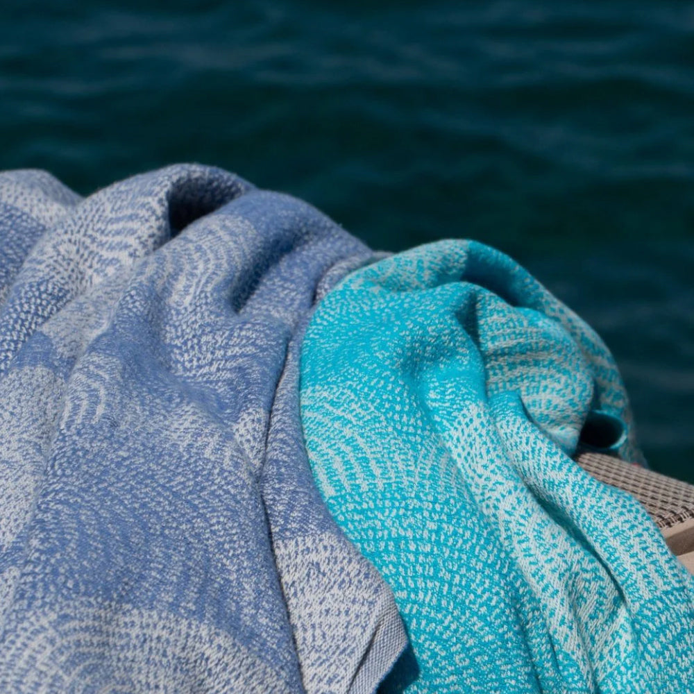 Close-up of blue and turquoise textured fabric against a blurred natural background