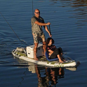 Man is paddling on inflatable stand up paddle board while a girl is sitting in a folding seat