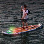 Lifestyle photo of a man paddleboarding with NIXY navigation lights attached to his board.